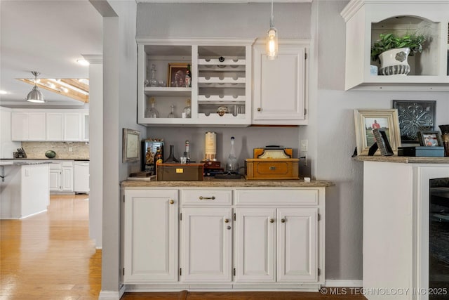 bar featuring white cabinetry, hanging light fixtures, light hardwood / wood-style flooring, white dishwasher, and decorative backsplash