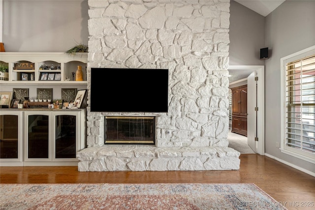 unfurnished living room with wood-type flooring, vaulted ceiling, and a fireplace