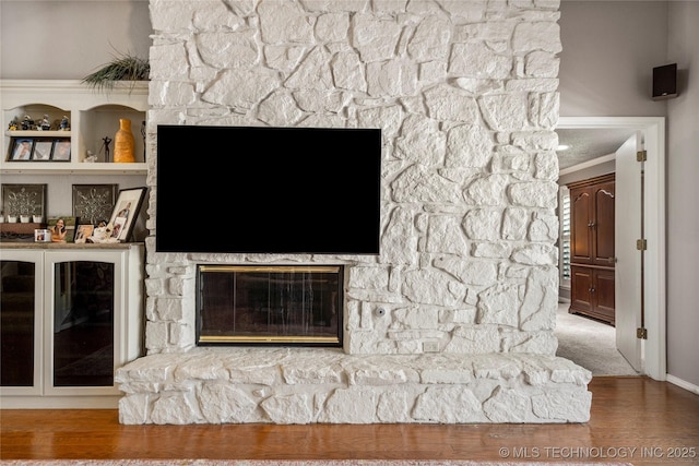 details with a stone fireplace, wood-type flooring, and ornamental molding