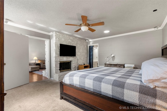 carpeted bedroom with crown molding, a stone fireplace, ceiling fan, and a textured ceiling