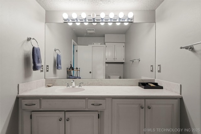 bathroom with vanity, toilet, and a textured ceiling