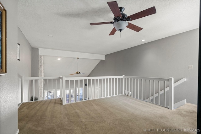 carpeted empty room featuring lofted ceiling with beams and a textured ceiling