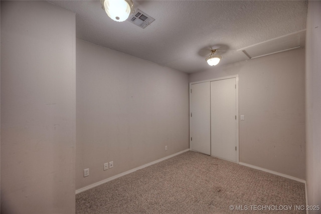 unfurnished bedroom featuring light colored carpet, a closet, and a textured ceiling