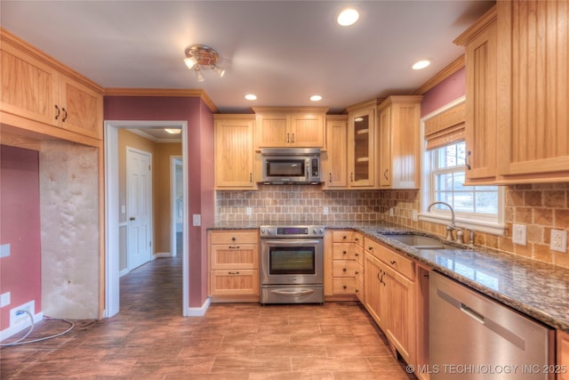 kitchen with sink, crown molding, appliances with stainless steel finishes, dark stone counters, and light brown cabinets