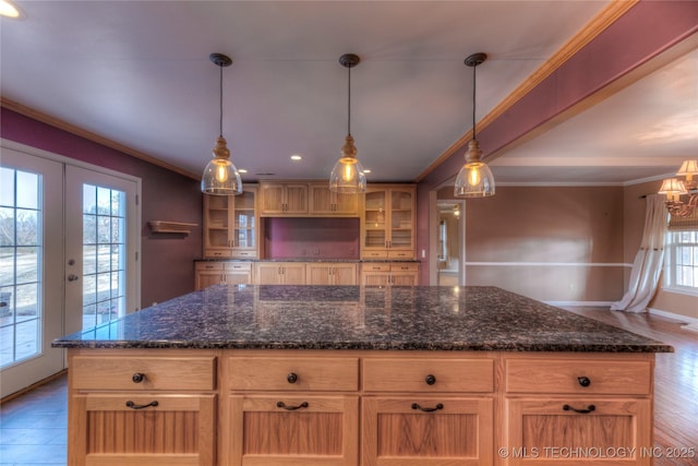 kitchen featuring pendant lighting, dark stone countertops, a center island, crown molding, and french doors