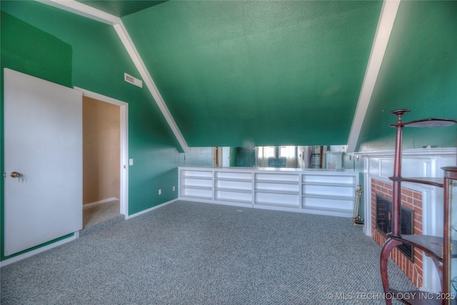 additional living space featuring lofted ceiling, a brick fireplace, and carpet floors