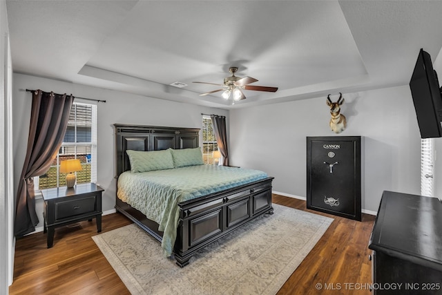 bedroom featuring ceiling fan, dark hardwood / wood-style floors, and a raised ceiling