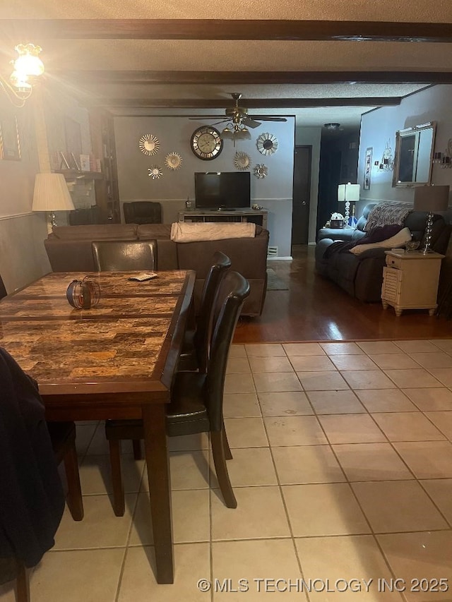 tiled dining room with beamed ceiling, ceiling fan, and a textured ceiling