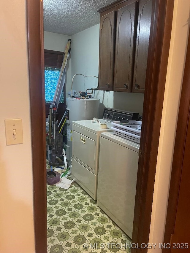 laundry room with water heater, washer and clothes dryer, cabinets, and a textured ceiling