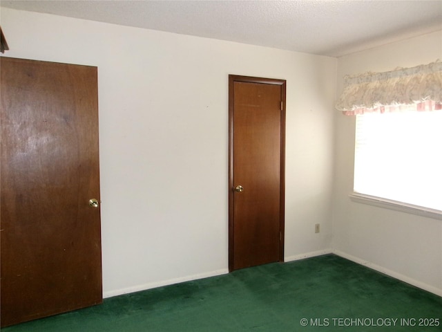 unfurnished bedroom with a textured ceiling, baseboards, and carpet flooring