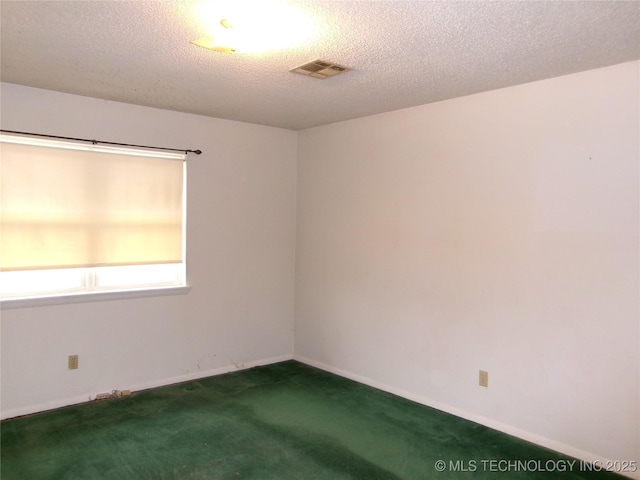 spare room with carpet, visible vents, a textured ceiling, and baseboards