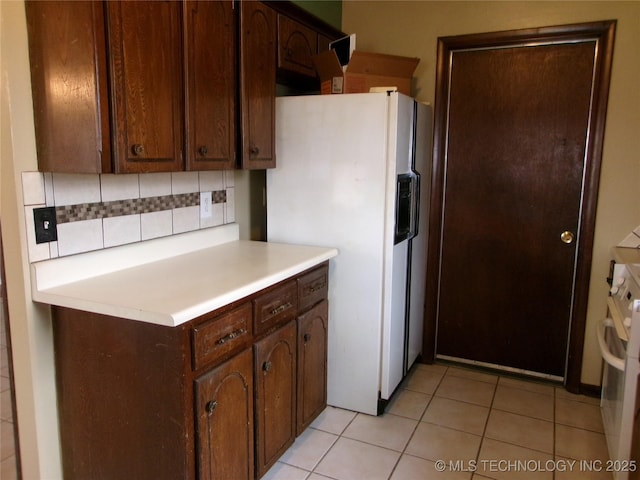 kitchen featuring light tile patterned floors, light countertops, white appliances, and backsplash