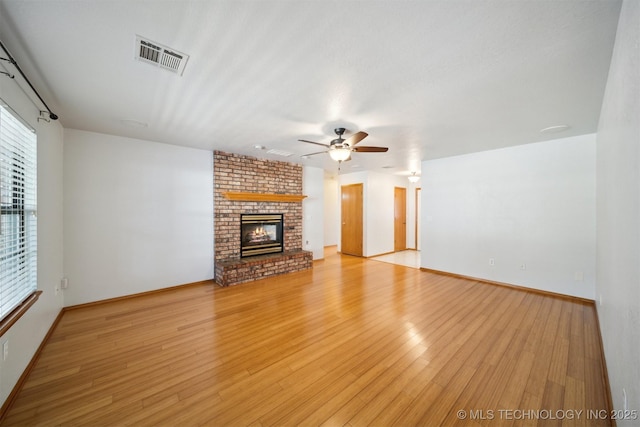 unfurnished living room featuring ceiling fan, a brick fireplace, and light hardwood / wood-style floors