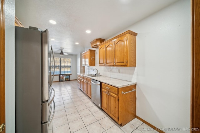 kitchen with sink, light tile patterned floors, ceiling fan, appliances with stainless steel finishes, and backsplash