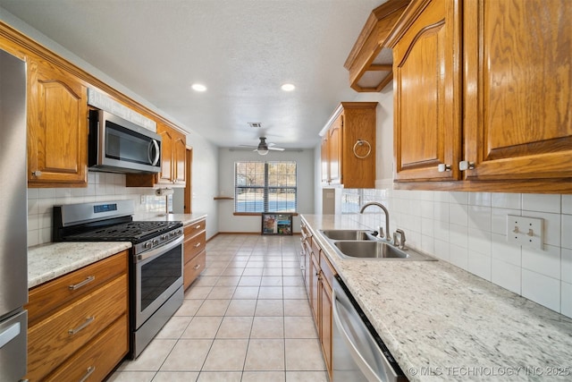 kitchen featuring tasteful backsplash, sink, light tile patterned floors, ceiling fan, and stainless steel appliances