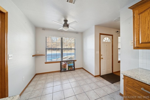 tiled entrance foyer featuring a textured ceiling and ceiling fan