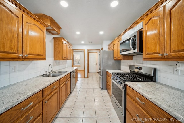 kitchen featuring light stone counters, sink, light tile patterned floors, and appliances with stainless steel finishes