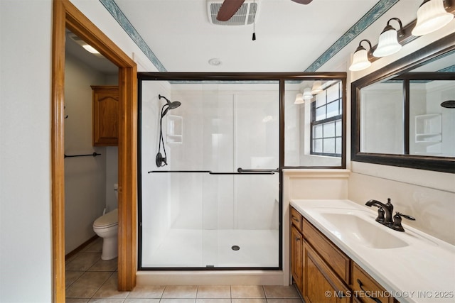 bathroom with ceiling fan, vanity, a shower with shower door, tile patterned floors, and toilet