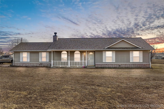 ranch-style home with a porch and a yard