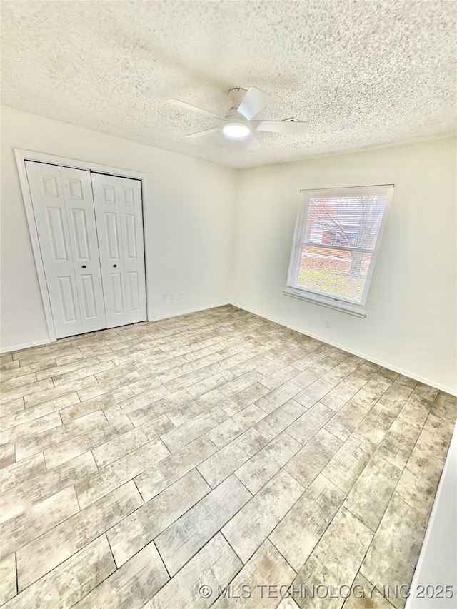 unfurnished bedroom featuring ceiling fan, a textured ceiling, a closet, and light wood-type flooring