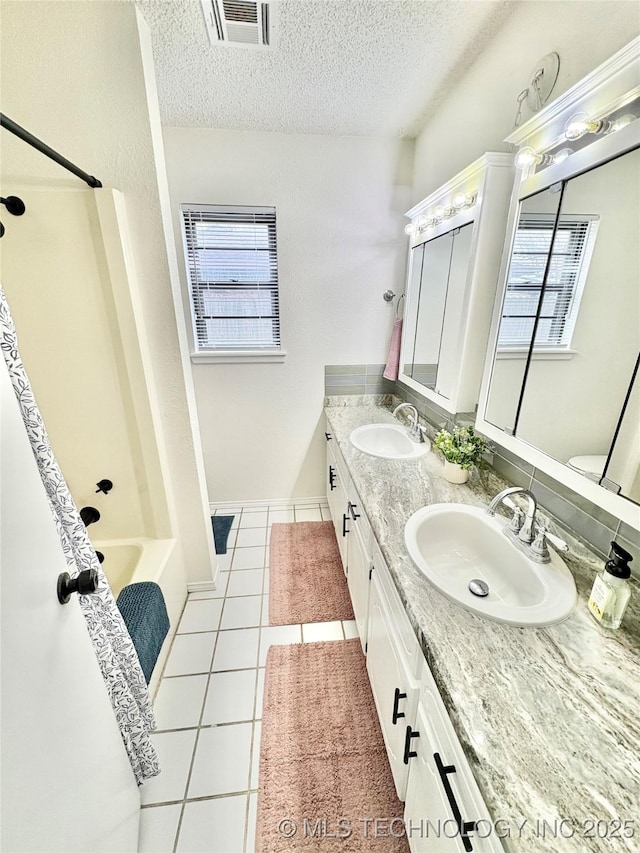 full bathroom with tile patterned flooring, vanity, a healthy amount of sunlight, and a textured ceiling