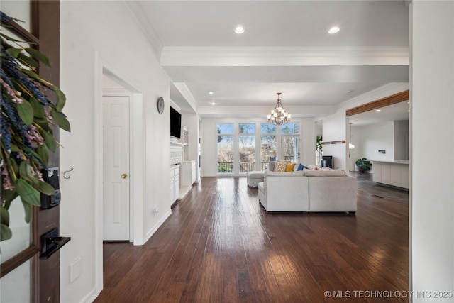 living room with crown molding, dark wood-type flooring, and an inviting chandelier