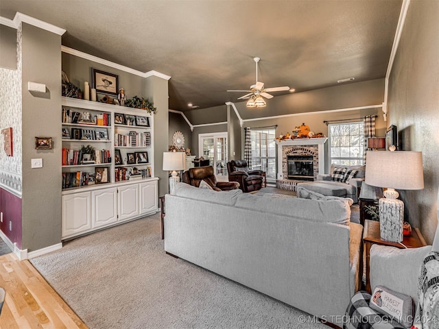 living room with crown molding, a fireplace, ceiling fan, and light wood-type flooring