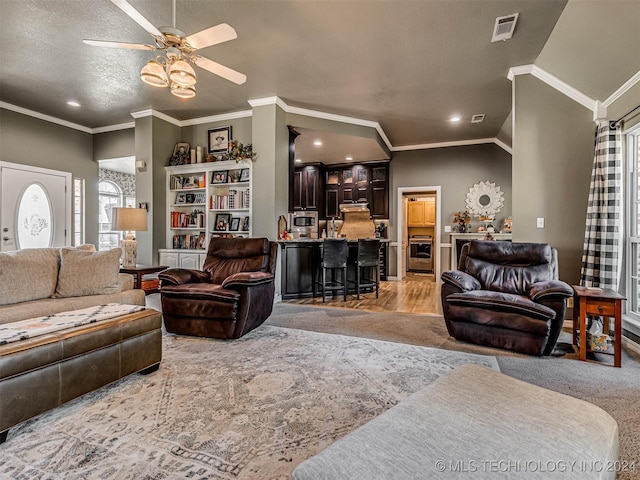 living room featuring ornamental molding, ceiling fan, and a textured ceiling