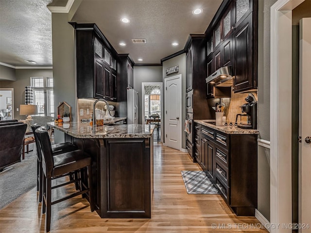 kitchen with light stone counters, sink, ornamental molding, and appliances with stainless steel finishes