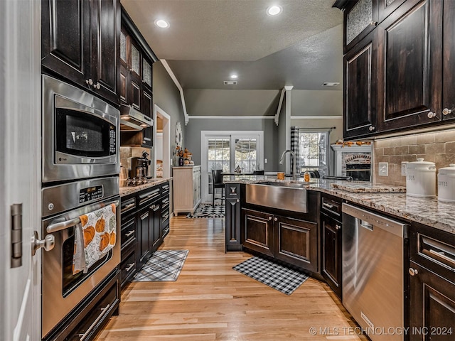 kitchen featuring sink, light hardwood / wood-style flooring, appliances with stainless steel finishes, light stone counters, and dark brown cabinetry