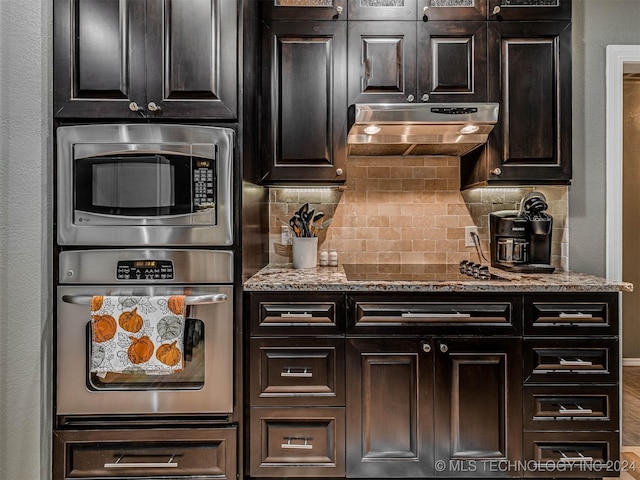 kitchen with dark brown cabinetry, stainless steel appliances, stone countertops, and backsplash