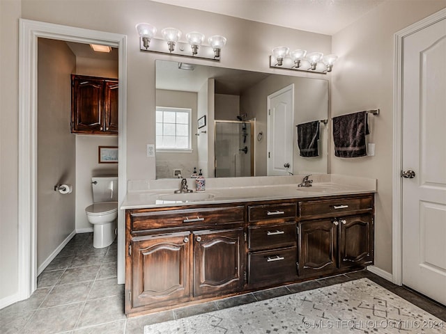 bathroom with a shower with door, vanity, tile patterned floors, and toilet