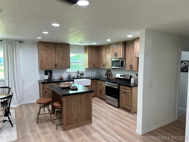 kitchen featuring a kitchen island, a breakfast bar, sink, stainless steel appliances, and light hardwood / wood-style flooring