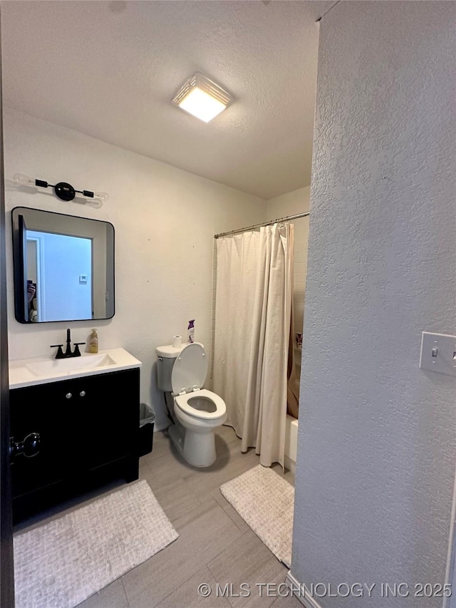 full bathroom featuring vanity, shower / bath combo, toilet, and a textured ceiling