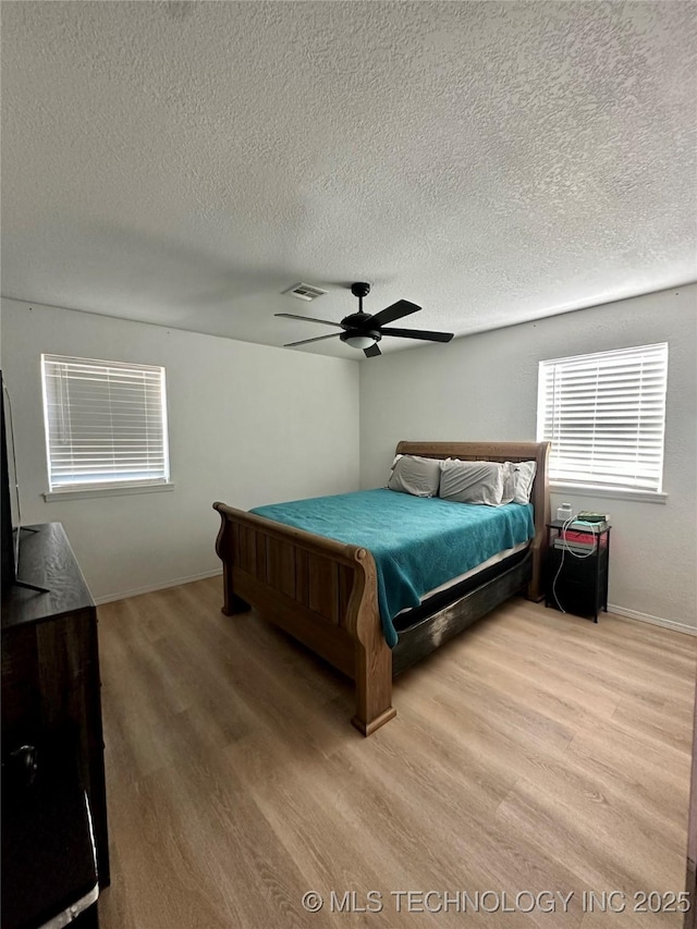 bedroom featuring a textured ceiling, ceiling fan, and light wood-type flooring