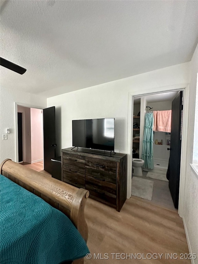 bedroom with light hardwood / wood-style flooring, a textured ceiling, and ensuite bathroom