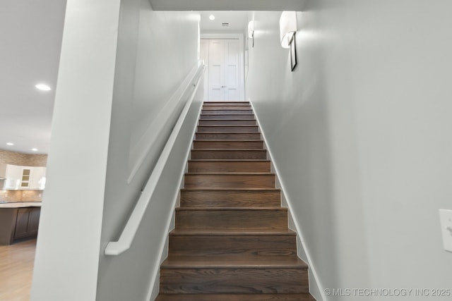 stairs with baseboards, wood finished floors, and recessed lighting