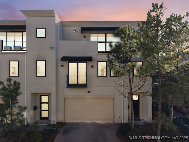 view of front facade with driveway, an attached garage, and stucco siding