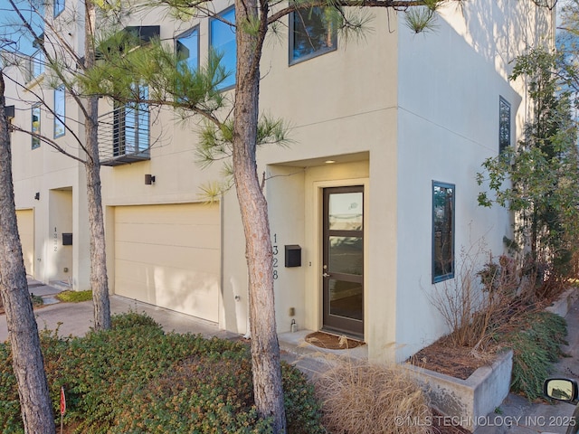 entrance to property with a garage and stucco siding