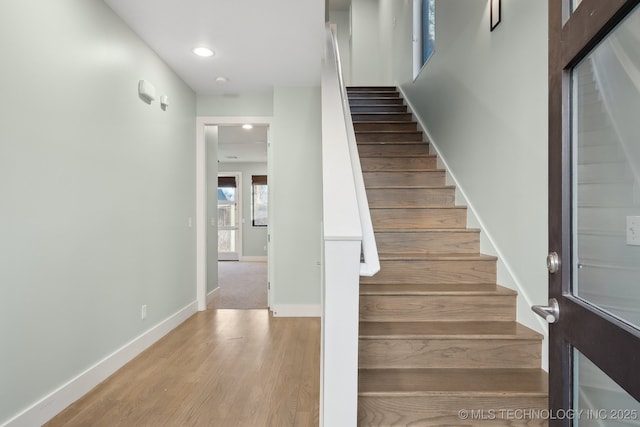 staircase featuring baseboards, wood finished floors, and recessed lighting