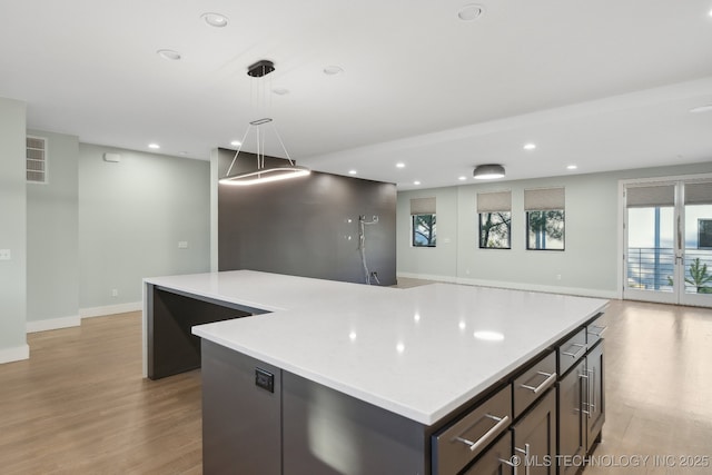 kitchen with decorative light fixtures, a kitchen island, and light hardwood / wood-style flooring