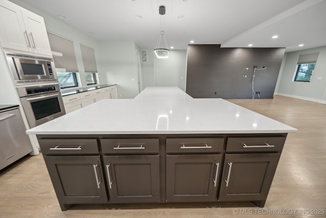 kitchen featuring appliances with stainless steel finishes, hanging light fixtures, a kitchen island, and white cabinets