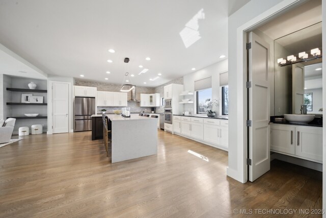 unfurnished living room with a large fireplace, a wealth of natural light, built in features, and light wood-type flooring