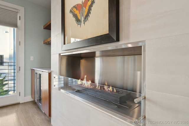 room details with a warm lit fireplace and wood finished floors