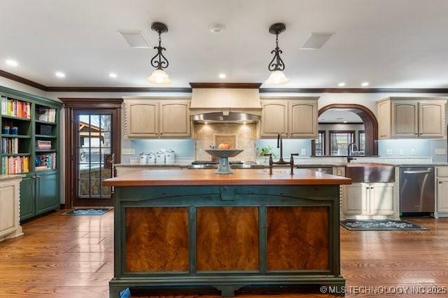 kitchen featuring dishwasher, exhaust hood, wooden counters, and decorative light fixtures