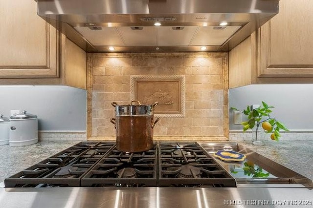 kitchen featuring light brown cabinetry, decorative backsplash, stainless steel gas cooktop, and wall chimney exhaust hood