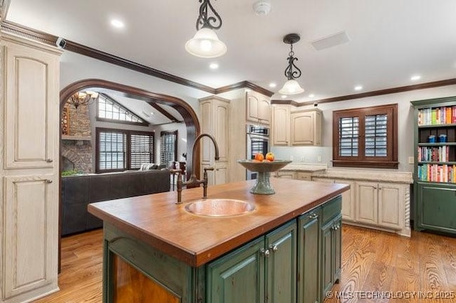 kitchen featuring pendant lighting, wooden counters, a kitchen island with sink, and light hardwood / wood-style flooring