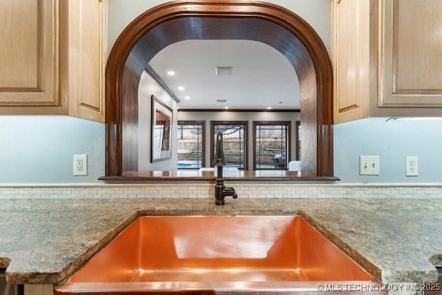 kitchen with stone counters, ornamental molding, and light brown cabinetry