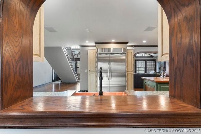 kitchen with built in refrigerator, kitchen peninsula, butcher block countertops, and cream cabinetry