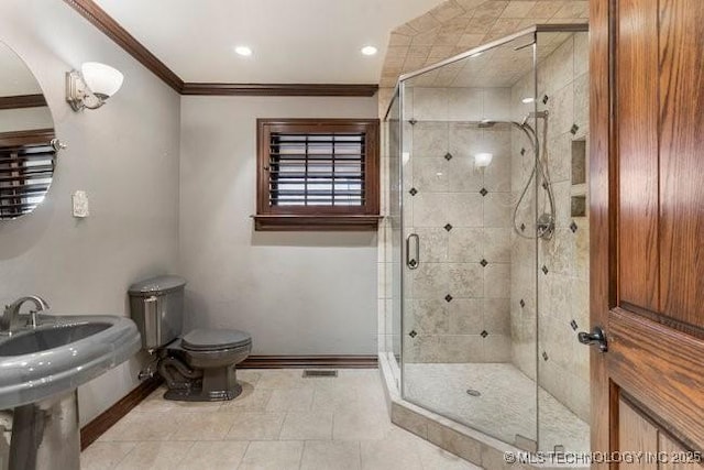 bathroom with tile patterned flooring, ornamental molding, toilet, and a shower with shower door